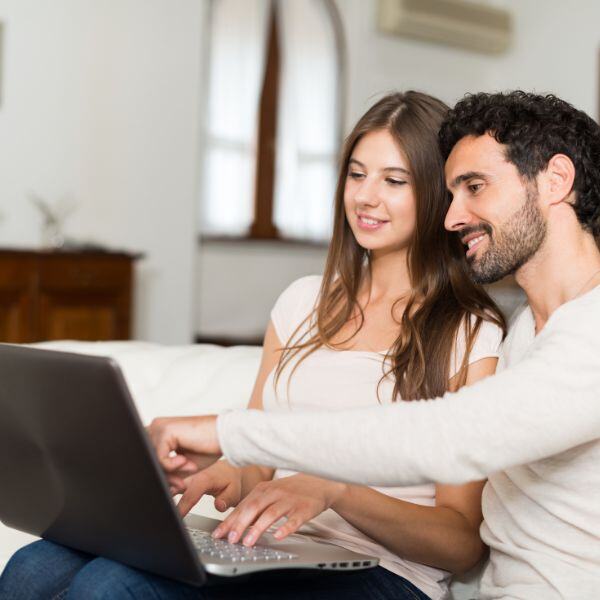 a couple smiling while looking at their computer